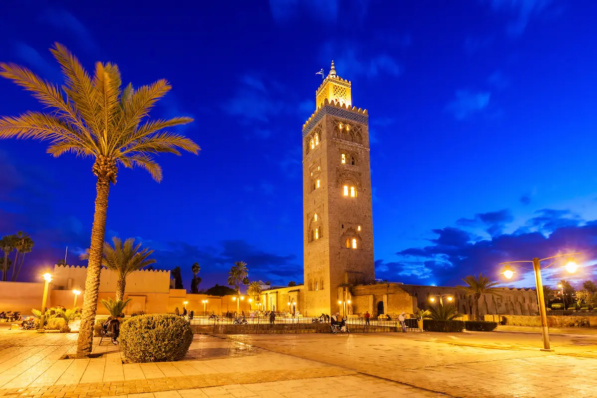 The Koutoubia Mosque minaret rising above palms against a clear blue sky in Marrakech